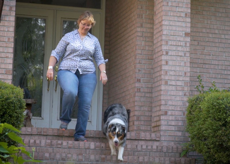 Women walking down the front steps of her house with her dog.
